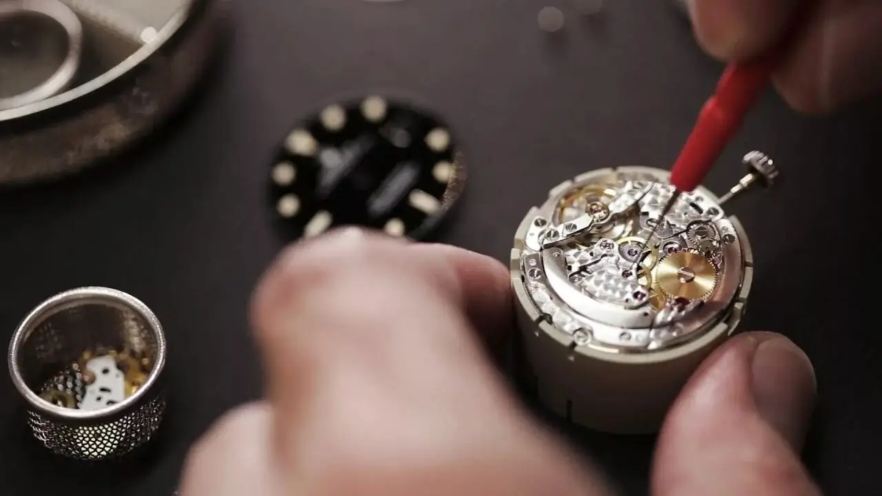 A watchmaker polishing a watch component by hand.